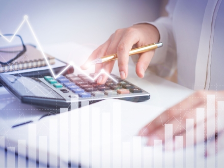 Accountant calculating profit with financial analysis graphs. Notebook, glasses and calculator lying on desk. Accountancy concept. Cropped view.